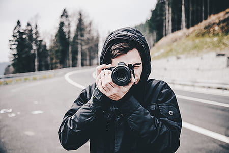 person wearing black zip-up jacket holding camera taking photo thumbnail