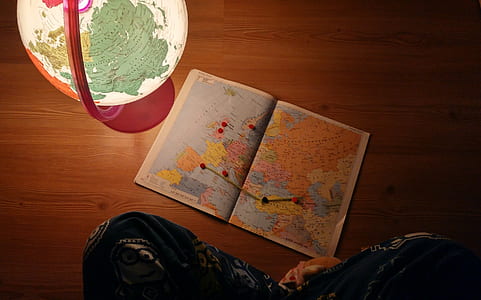 person sitting on floor with map beside glowing globe thumbnail