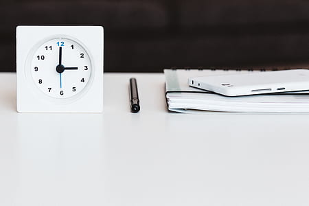 white and black analog clock reading 3 near black pen thumbnail