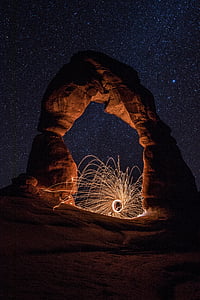steel wool photography on rock formation at night thumbnail