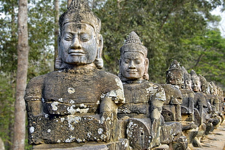 gray Buddha statues near trees during daytime thumbnail