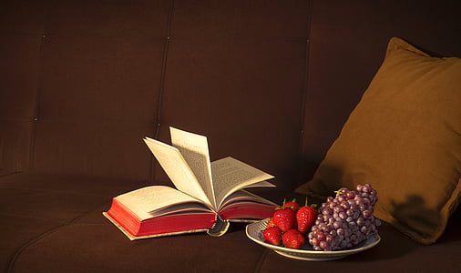 opened book beside plate filled with strawberries and grapes thumbnail