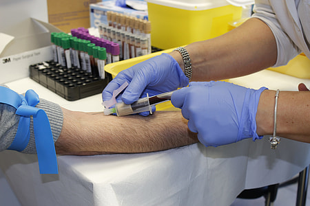 person wearing blue disposable gloves injecting syringe thumbnail
