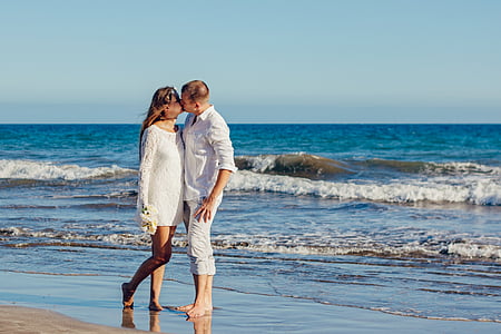 woman and man standing on shoreline kissing thumbnail