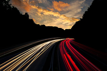 low-exposure photo of light of vehicles on road under yellow cloudy sky thumbnail