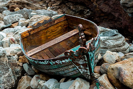 brown and white wooden boat on brown and white stone fragments thumbnail