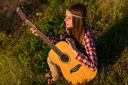 woman in red and white checked sport shirt holding dreadnought brown acoustic guitar thumbnail