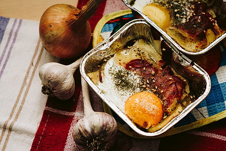 Cooked Food in Square Grey Tray Beside Garlics and Onion thumbnail