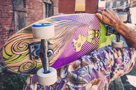 person holding purple and green cruiser board thumbnail