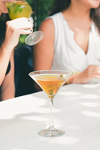 Clear Cocktail Glass Filled With Liquor on White Table thumbnail
