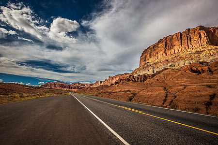 brown concrete roadway near brown mountain under white clouds at daytime thumbnail