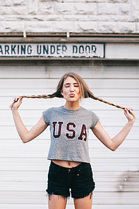 woman in gray crew-neck crop top and black denim short shorts standing behind white door during daytime thumbnail