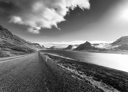 grayscale photo of road beside body of water thumbnail