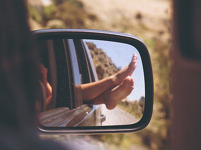 reflection of woman's feet in car side mirror thumbnail