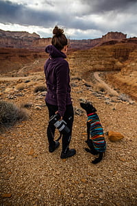 woman with black dog standing near mountains during daytime thumbnail