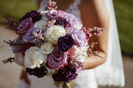 shallow focus photography of woman holding white and purple flowers thumbnail
