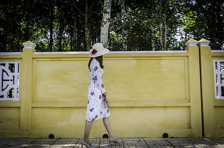 woman walking near yellow concrete wall thumbnail