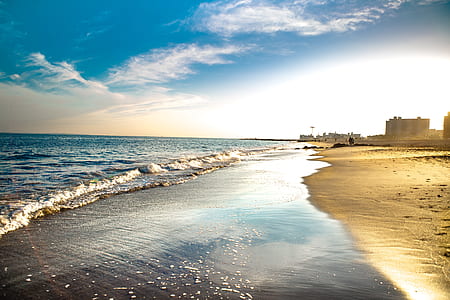 body of water and seashore under cloudy sky thumbnail