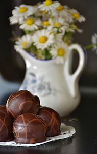 chocolates beside daisy flowers in vase thumbnail