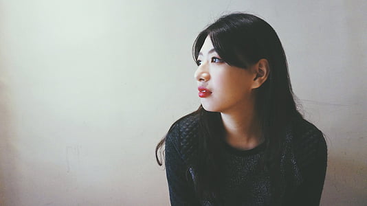 woman sitting near white wall thumbnail