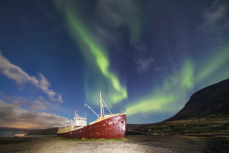 photograph of Northern Lights over red and white ship on shore thumbnail