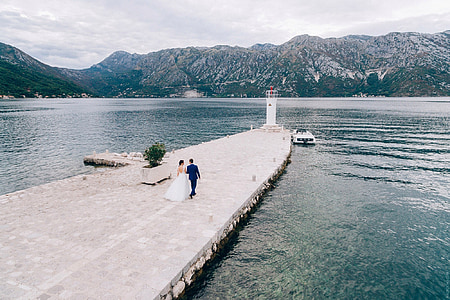 bride and groom walking on dock during daytime thumbnail
