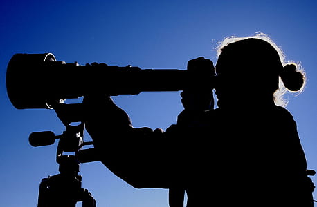 silhouette photo of woman holding telescope thumbnail