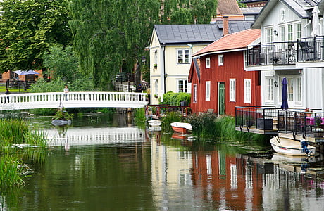 white boat in body of water near house thumbnail