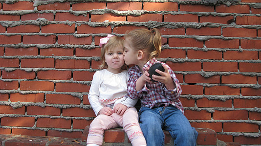 girl in pink and white plaid shirt kissing girl in white long-sleeve shirt and pink pants thumbnail