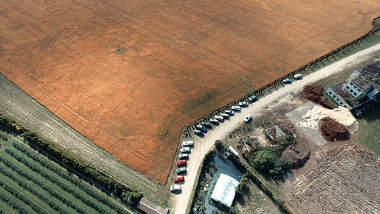 bird's-eye view photography of parked vehicles near crop field thumbnail