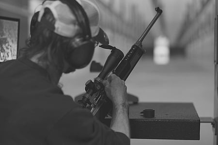 grayscaled photo of man holding rifle thumbnail