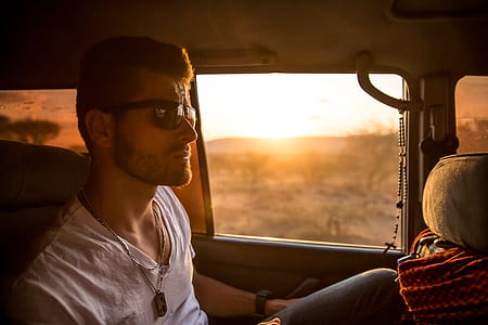 person in white shirt sitting inside car during golden hour thumbnail