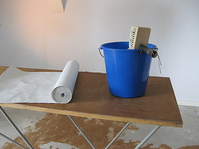 brown brush in blue plastic bucket placed on top of brown table thumbnail