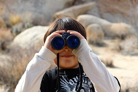 boy with black and white crew-neck long-sleeved shirt using black binocular scope during daytime thumbnail