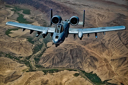 Gray Jet Fighter Flying Above Brown Mountain thumbnail
