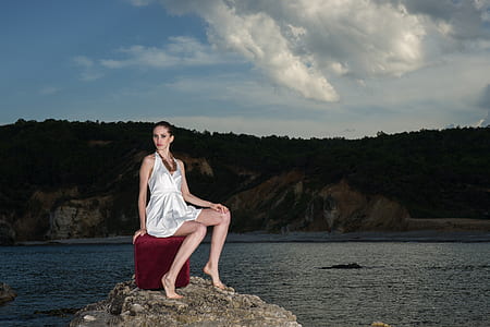 woman in white halterneck mini dress sitting on red box thumbnail