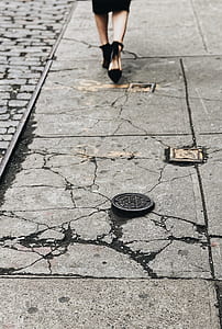 woman wearing pair of black pointed-toe ankle strap pumps walking on gray pavement thumbnail