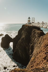 white lighthouse on mountain over body of water thumbnail
