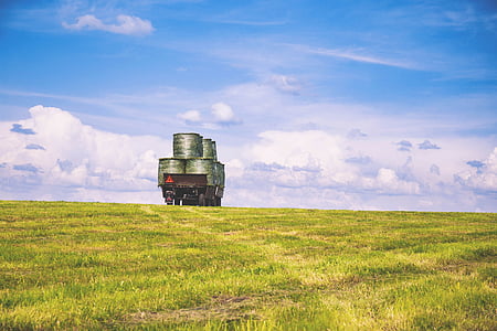 green barrel on green grass field under cumulus clouds thumbnail