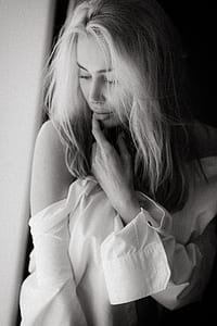 grayscale photography of woman wearing off shoulders posing beside curtain thumbnail