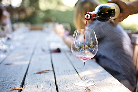 person pouring clear long-stem glass with red wine thumbnail