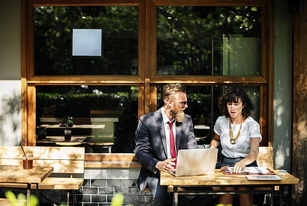 man and woman sitting on bench in front of brown wooden table behind the window during daytime thumbnail