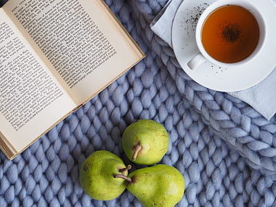 three pears fruits beside open book and ceramic mug with saucer thumbnail