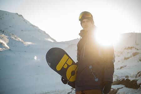 Man in Blue Pullover Hoodie Holding Blue and Yellow Snowboard thumbnail