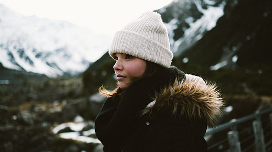 black haired woman in black parka jacket wearing white beanie in tilt shift photography thumbnail