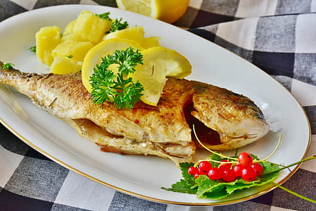 fried fish with sliced citrus fruits in white ceramic bowl thumbnail
