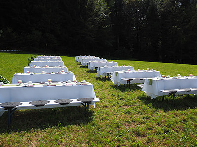 twelve wooden tables with table cloth on grass field during daytime thumbnail