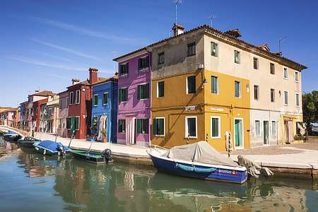 white speedboat near beige and white painted high-rise building under blue sky thumbnail