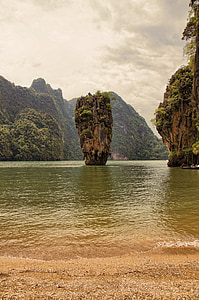 rock formation on large body of water under gray sky thumbnail