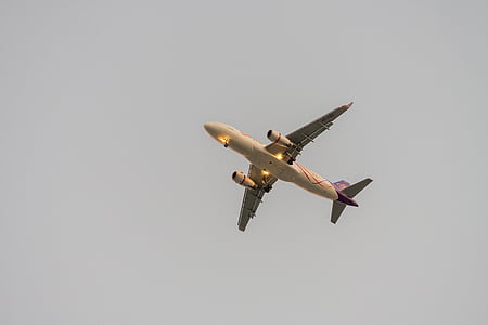 beige and red airplane under gray skies thumbnail